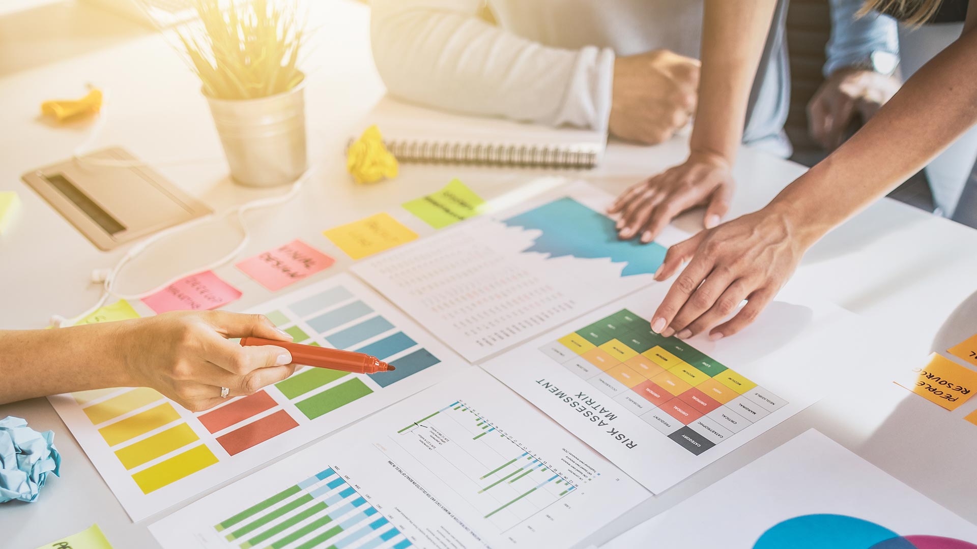 a team of people collaborate over a table filled with notes and charts to show business planning in action