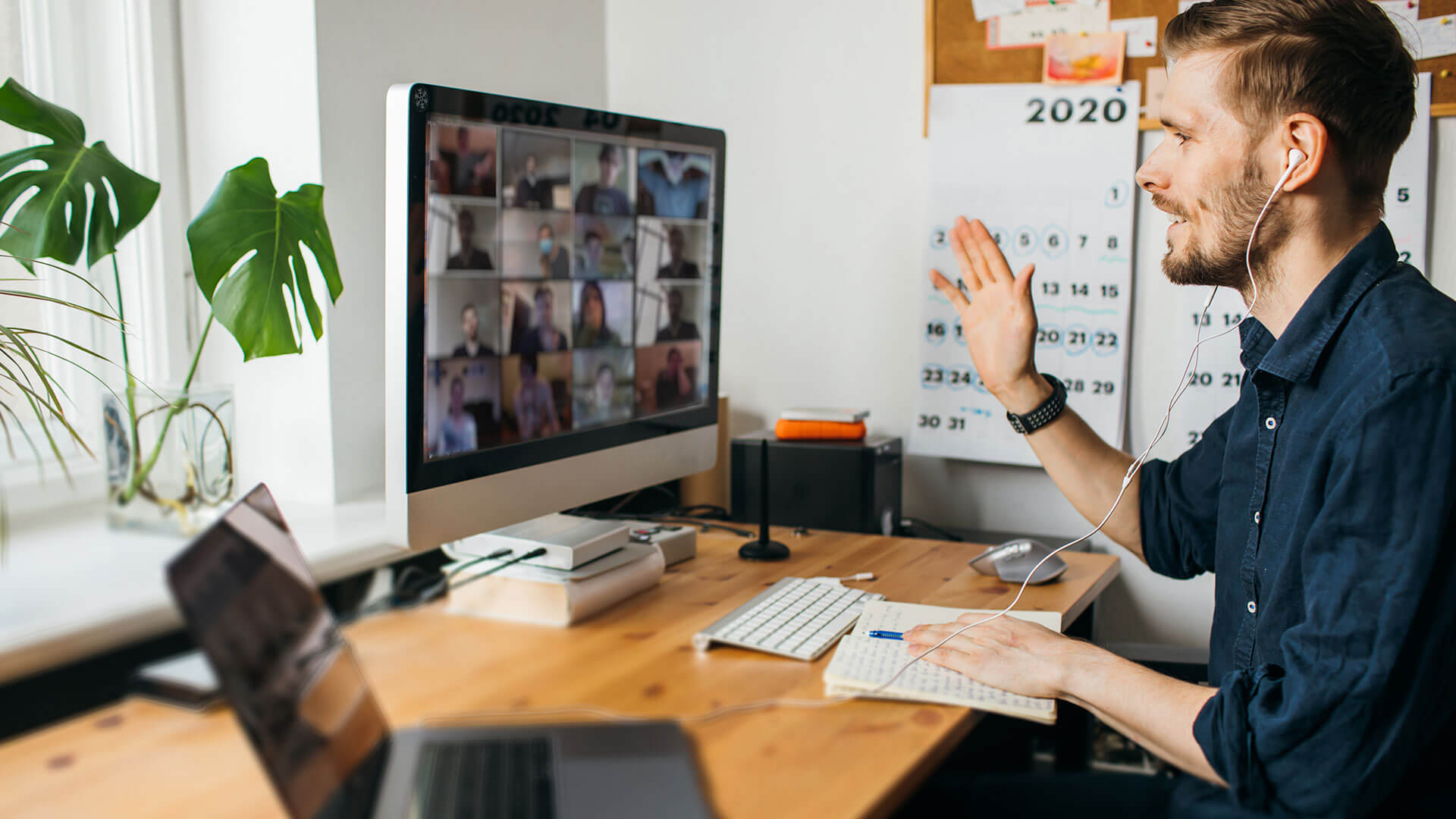 Community Service Organisations: Young man sits at computer on zoom call with colleagues as they work from home.