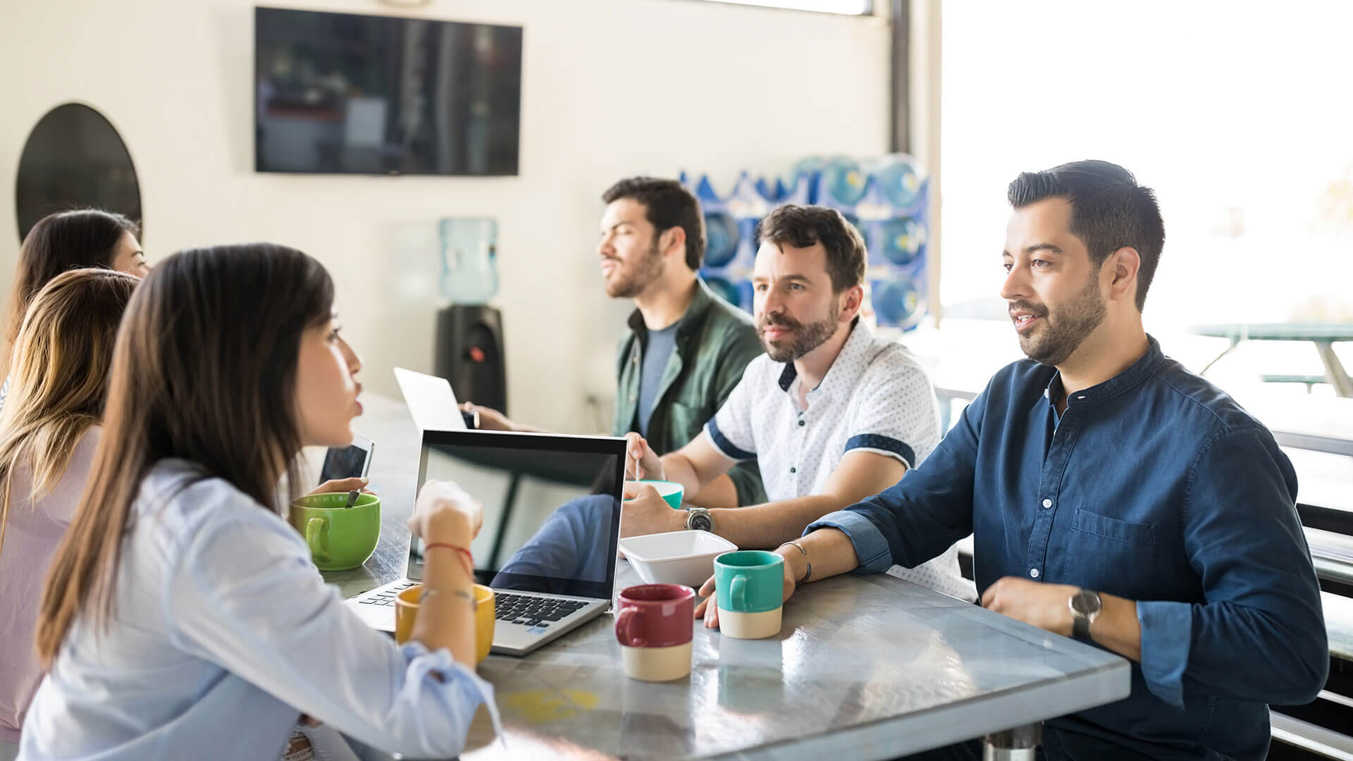 Team culture in the workplace: A group of young professionals sit in discussion around a computer desk