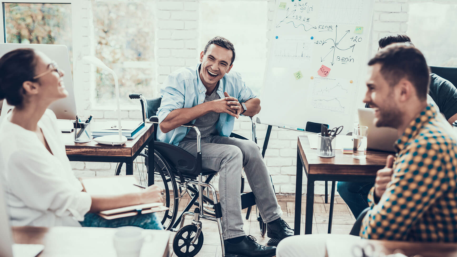 An NDIS Provider Marketing team sit in a group laughing as they set in place a Marketing Plan