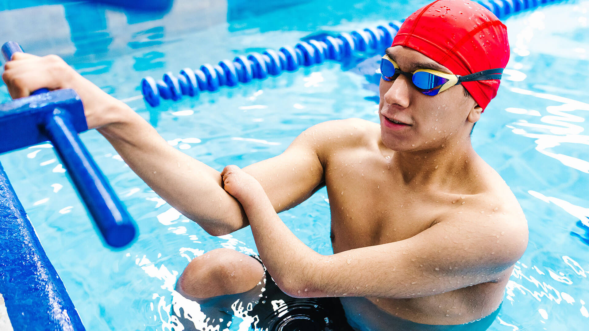 A disabled man holds on to pool ladder. Image used to illustrate the topic of inclusion.